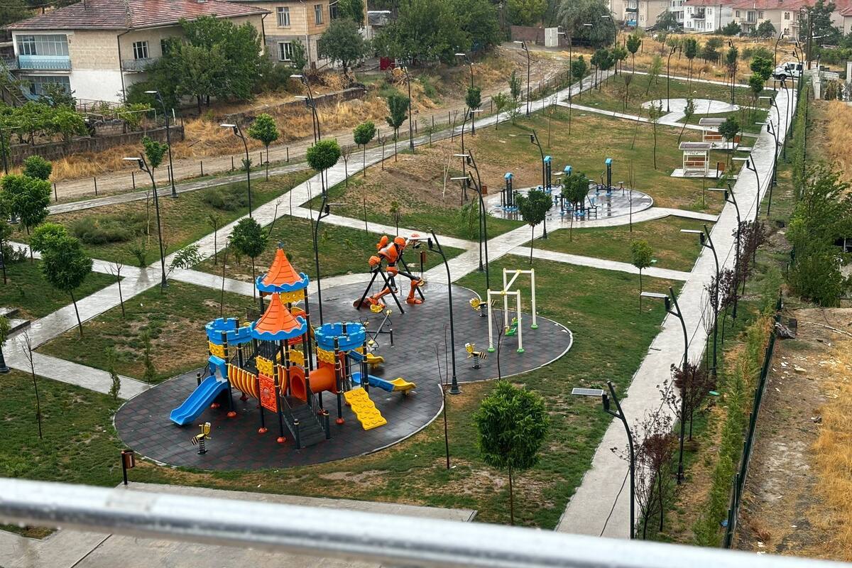 A playground with a castle play structure, exercise equipment, and a walking path.