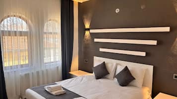 Una habitación de hotel moderna con una cama grande, una mesita de noche y una lámpara de pared.