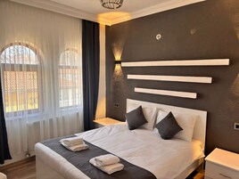 Una habitación de hotel moderna con una cama grande, una mesita de noche y una lámpara de pared.