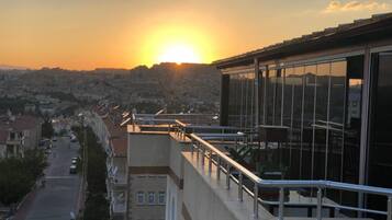 A building with a balcony overlooking a cityscape during sunset.