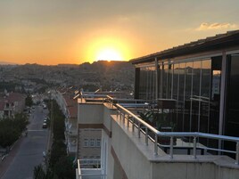 Un edificio con balcón que ofrece vistas a un paisaje urbano al atardecer.