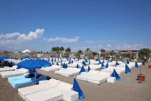 A beach with rows of white sunbeds and blue umbrellas. - Awen Lara Hotel (Antalya)