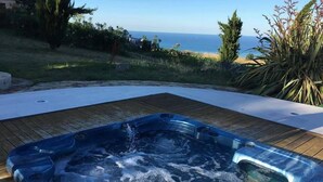 Uma banheira de hidromassagem com um deck de madeira e vista para o oceano.