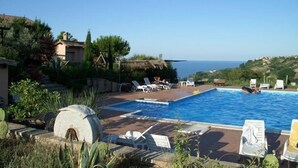 Área da piscina com espreguiçadeiras e vista para o mar.