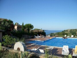 Una piscina al aire libre, sombrillas, sillones reclinables de piscina
