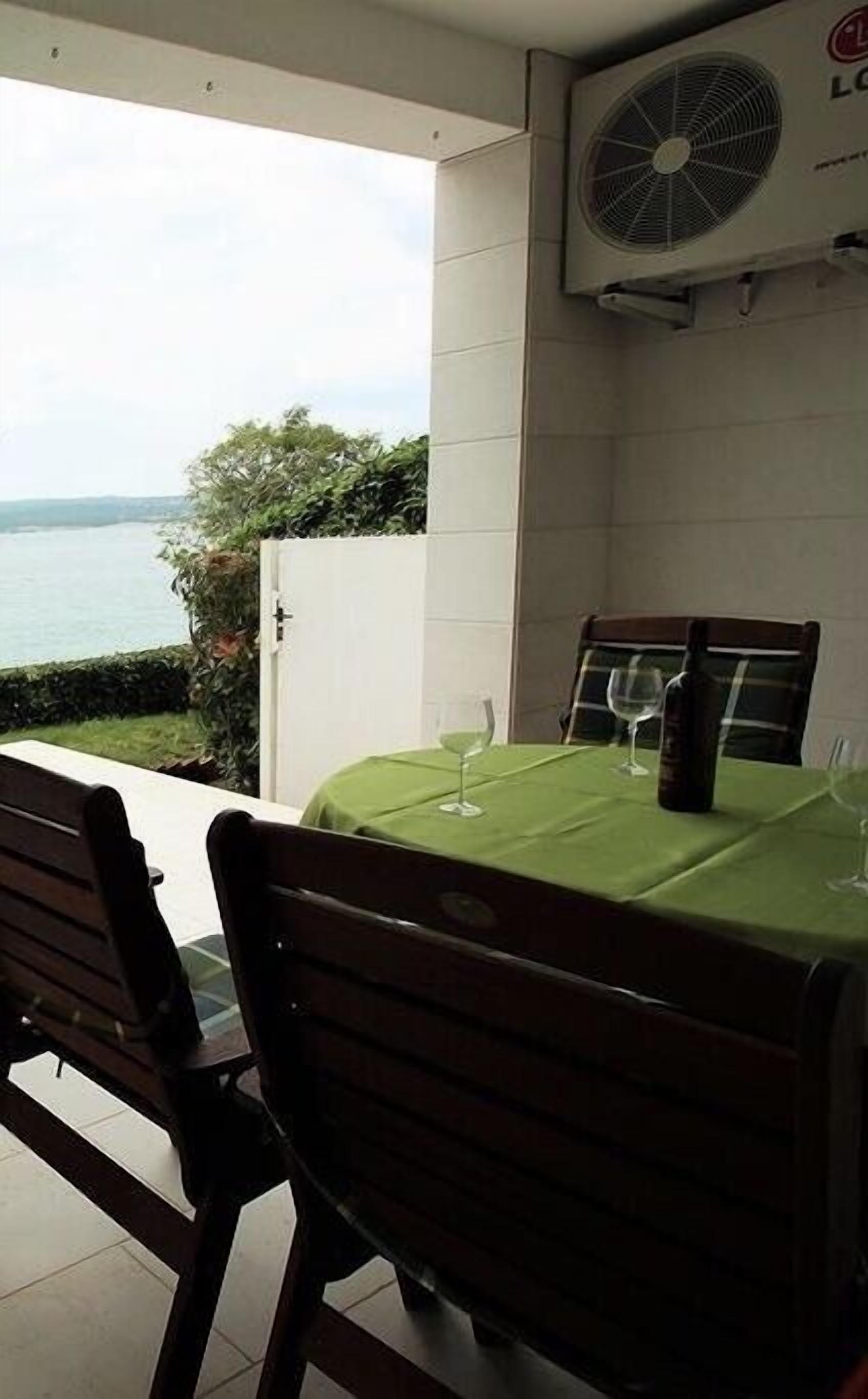 An outdoor dining area with a table set for two, a chair, and a view of the sea.