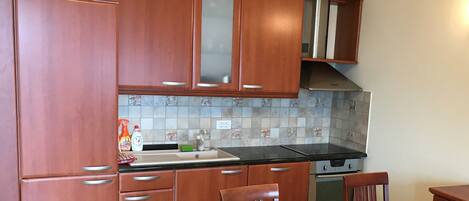 A kitchen with wooden cabinets, a black countertop, and a dining table with chairs.
