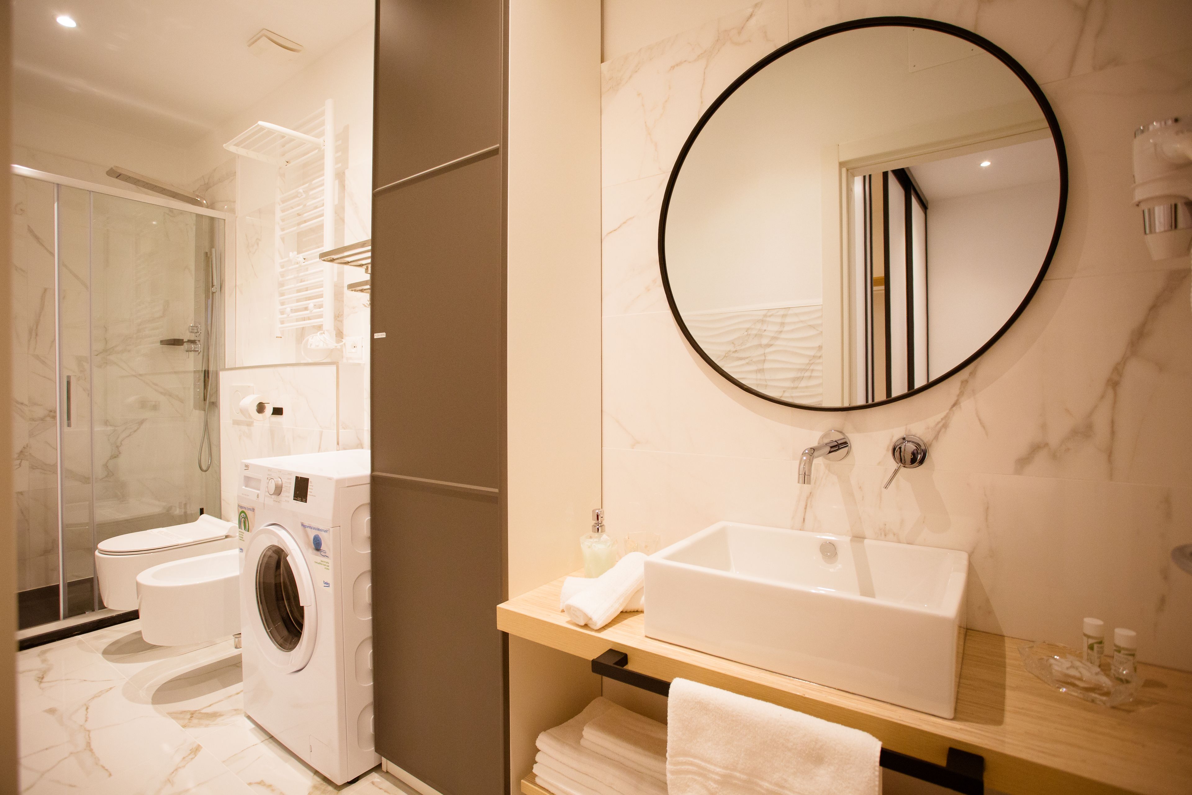 Une salle de bain moderne équipée d’un lave-linge intégré, d’un grand lavabo et d’un miroir.