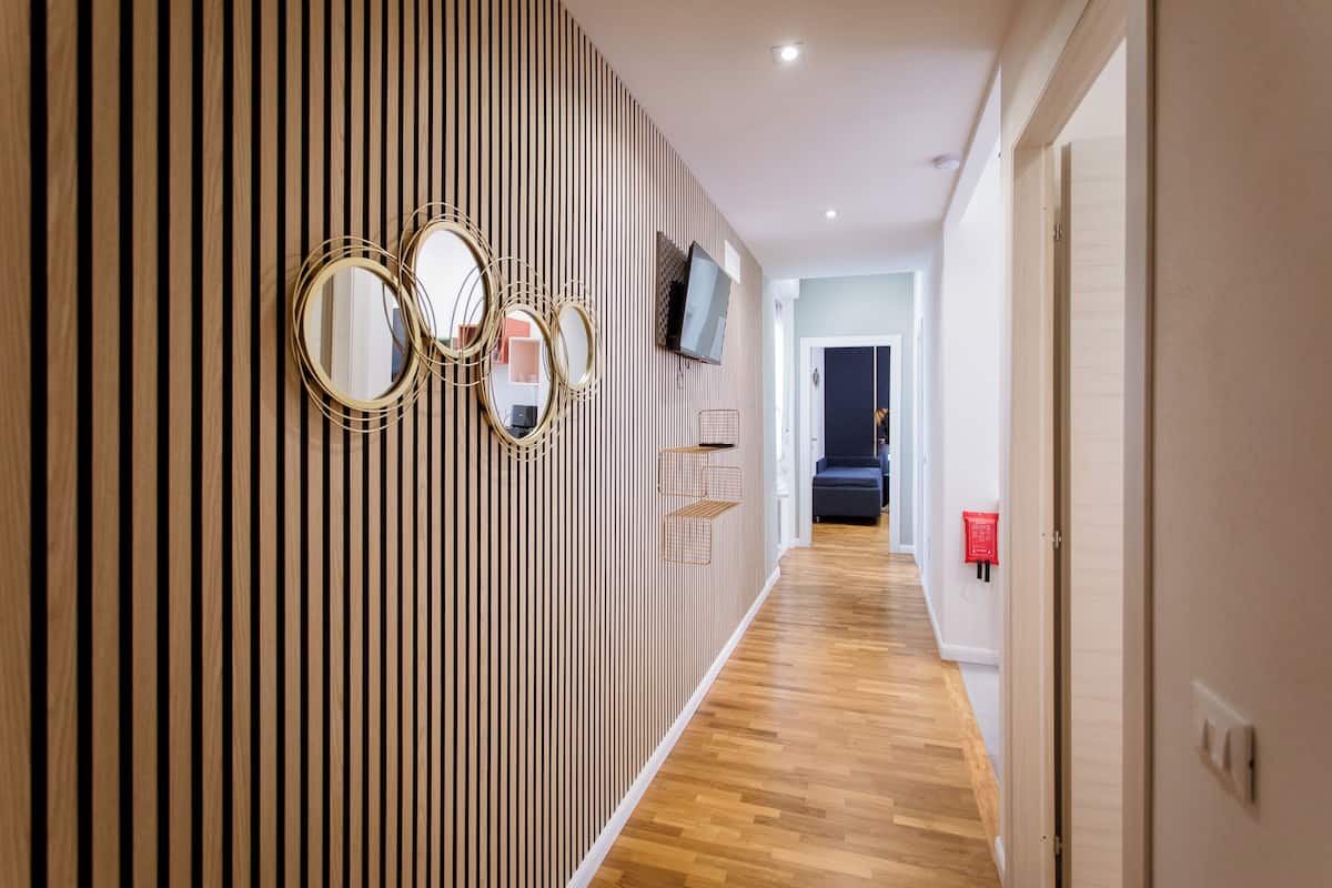 Ein Korridor mit Holzwandverkleidung, einem an der Wand befestigten Flachbildfernseher und einem Rauchmelder auf der rechten Seite.