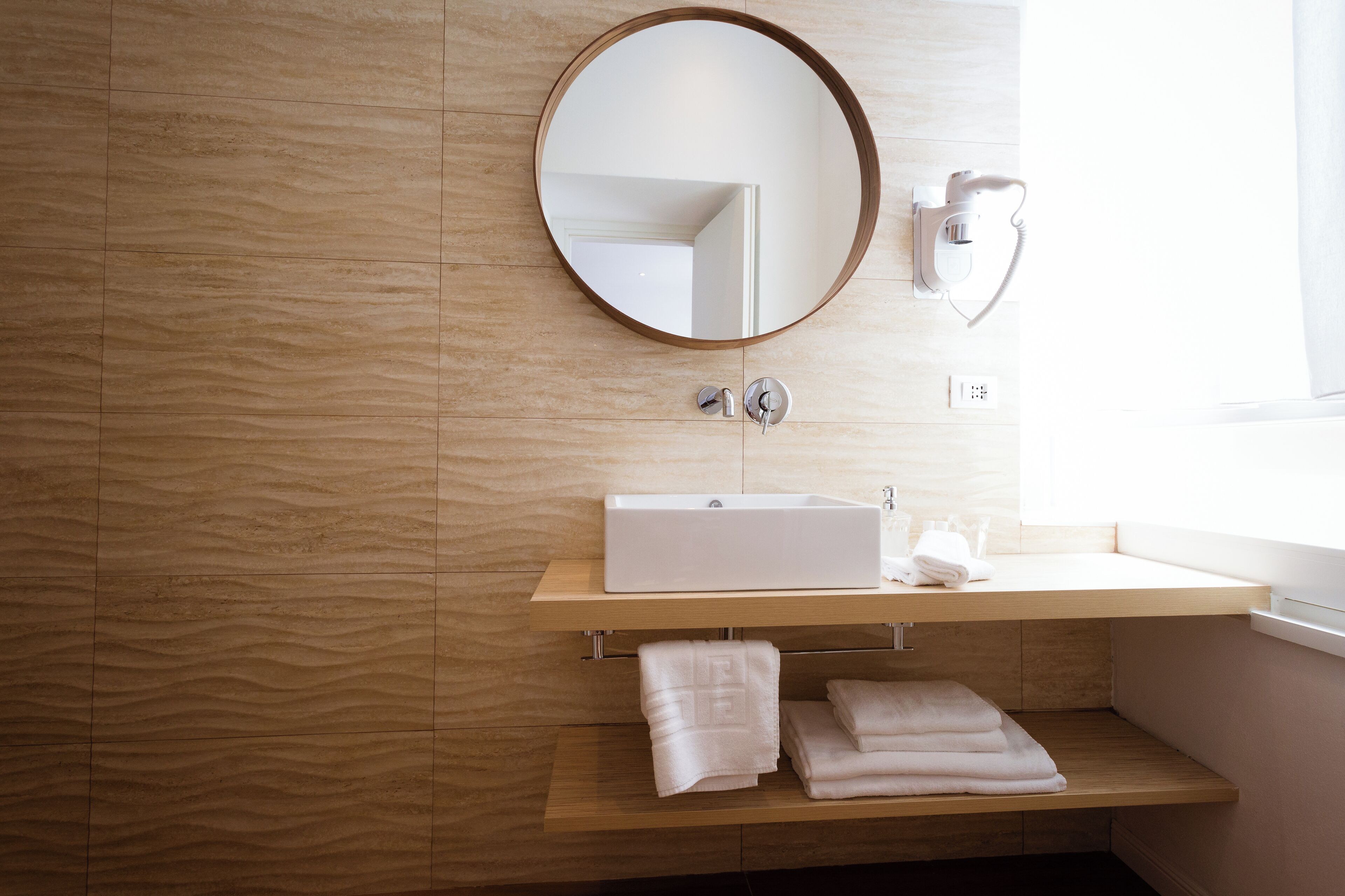 Une salle de bain moderne avec un meuble-lavabo en bois, un miroir rond et un lavabo intégré.