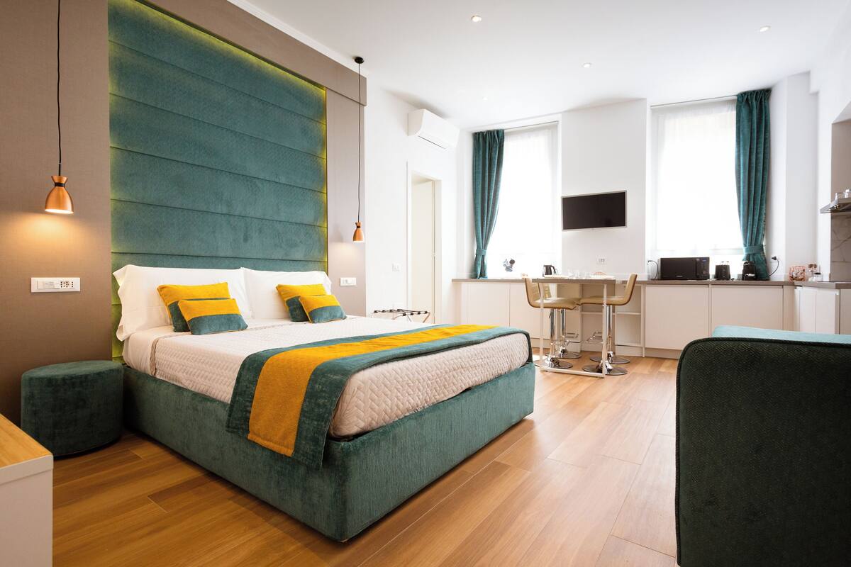 Ein modernes Hotelzimmer mit einem großen Bett, einem Schreibtisch und einer Küchenzeile.