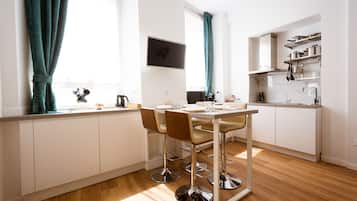 Une cuisine moderne avec des meubles blancs, un plan de travail en acier inoxydable et un coin repas comprenant une table et des chaises.
