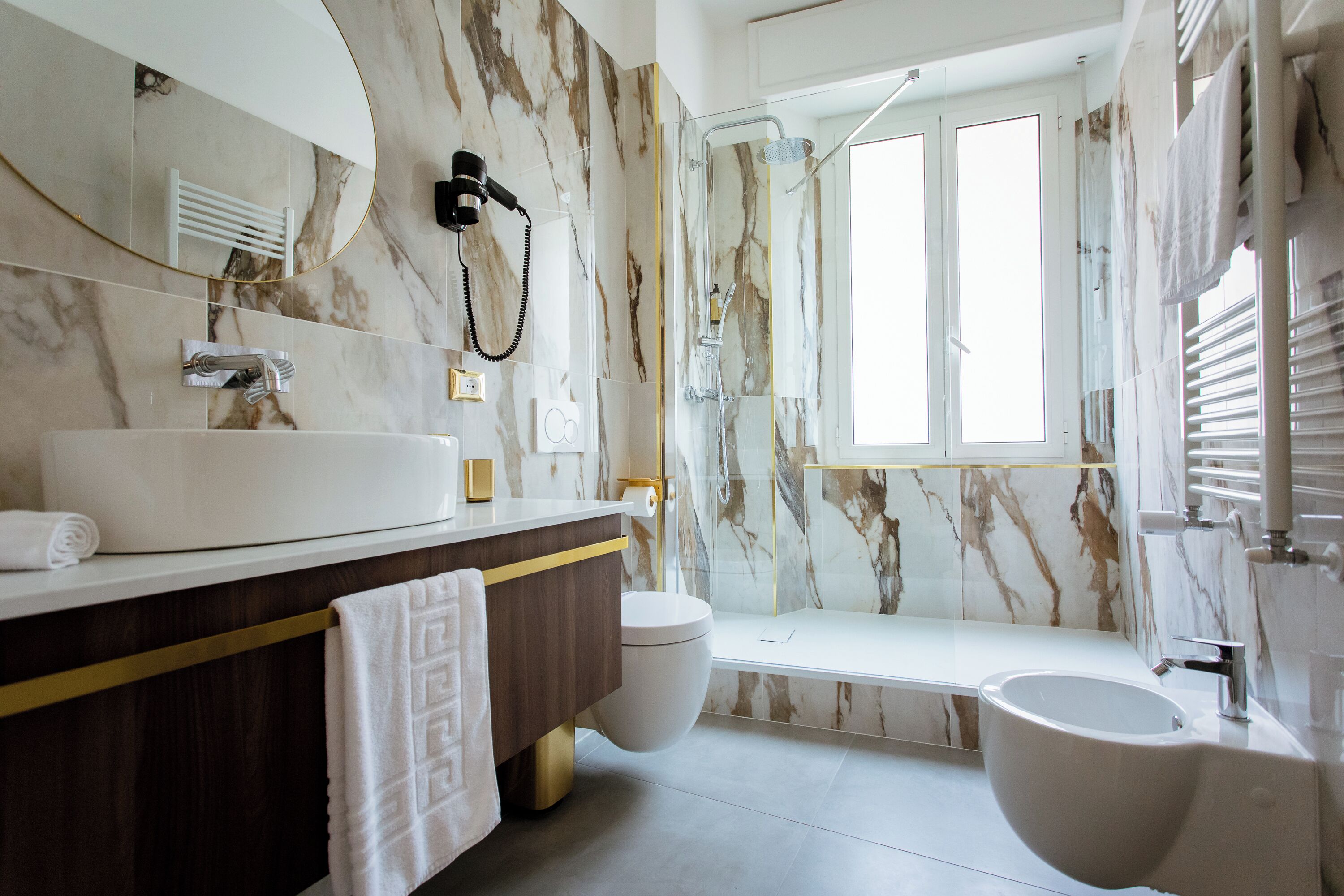 A modern bathroom with a marble vanity, a bidet, a bathtub, and a shower.