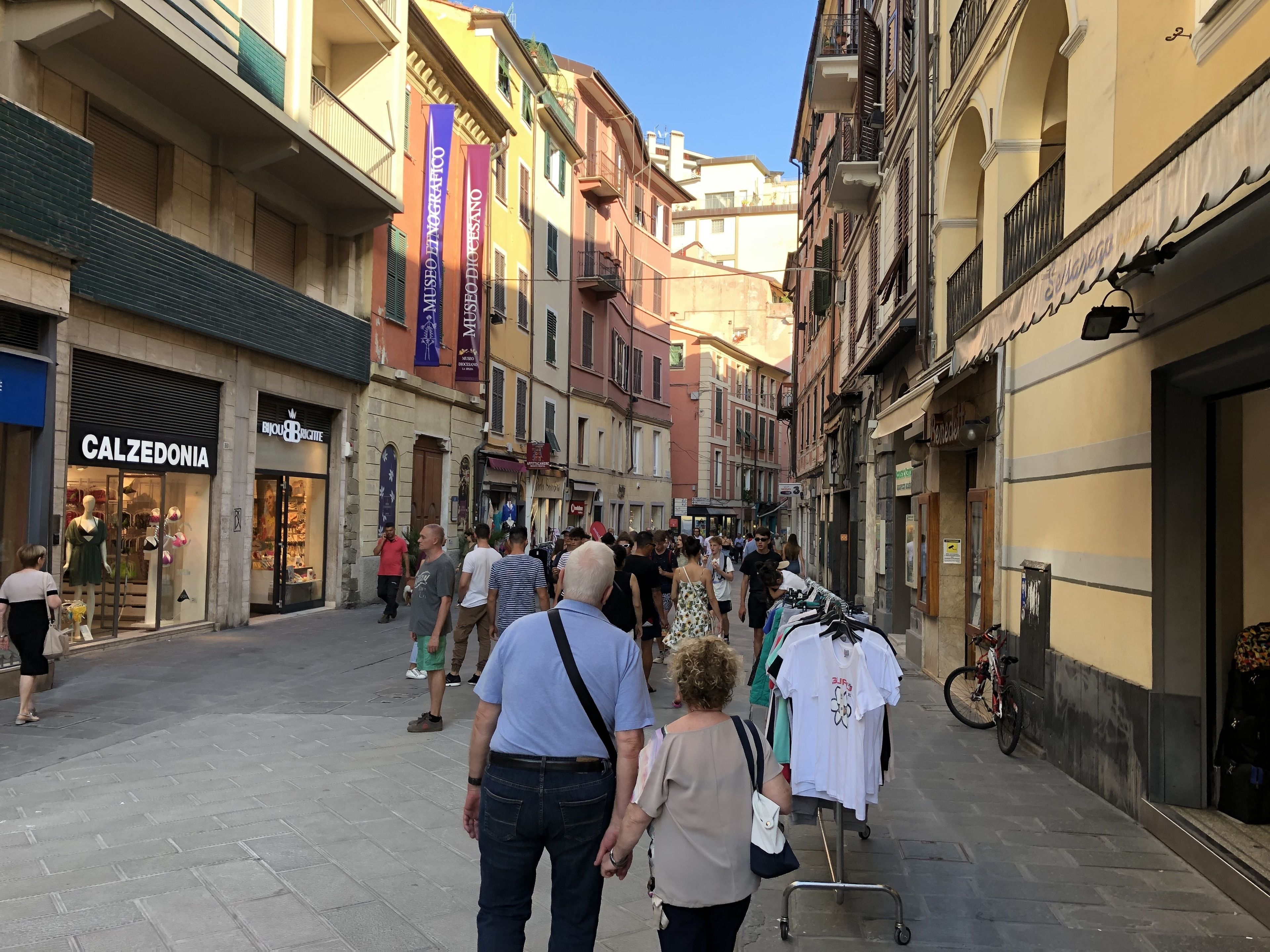 A bustling street with shops and a clothing rack.