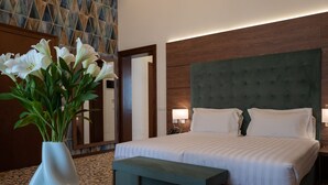 A hotel room with a large bed, a bench, a vase with flowers, and a wall with a geometric pattern. - Palazzo Scamozzi (Vicenza)