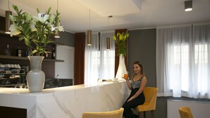 A modern kitchen with marble countertops, a bar area, and a seating area with yellow chairs. - Palazzo Scamozzi (Vicenza)