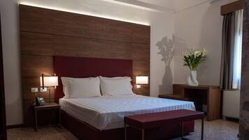A hotel room with a large bed, bedside lamps, a bedside phone, a small table, and a vase with flowers.