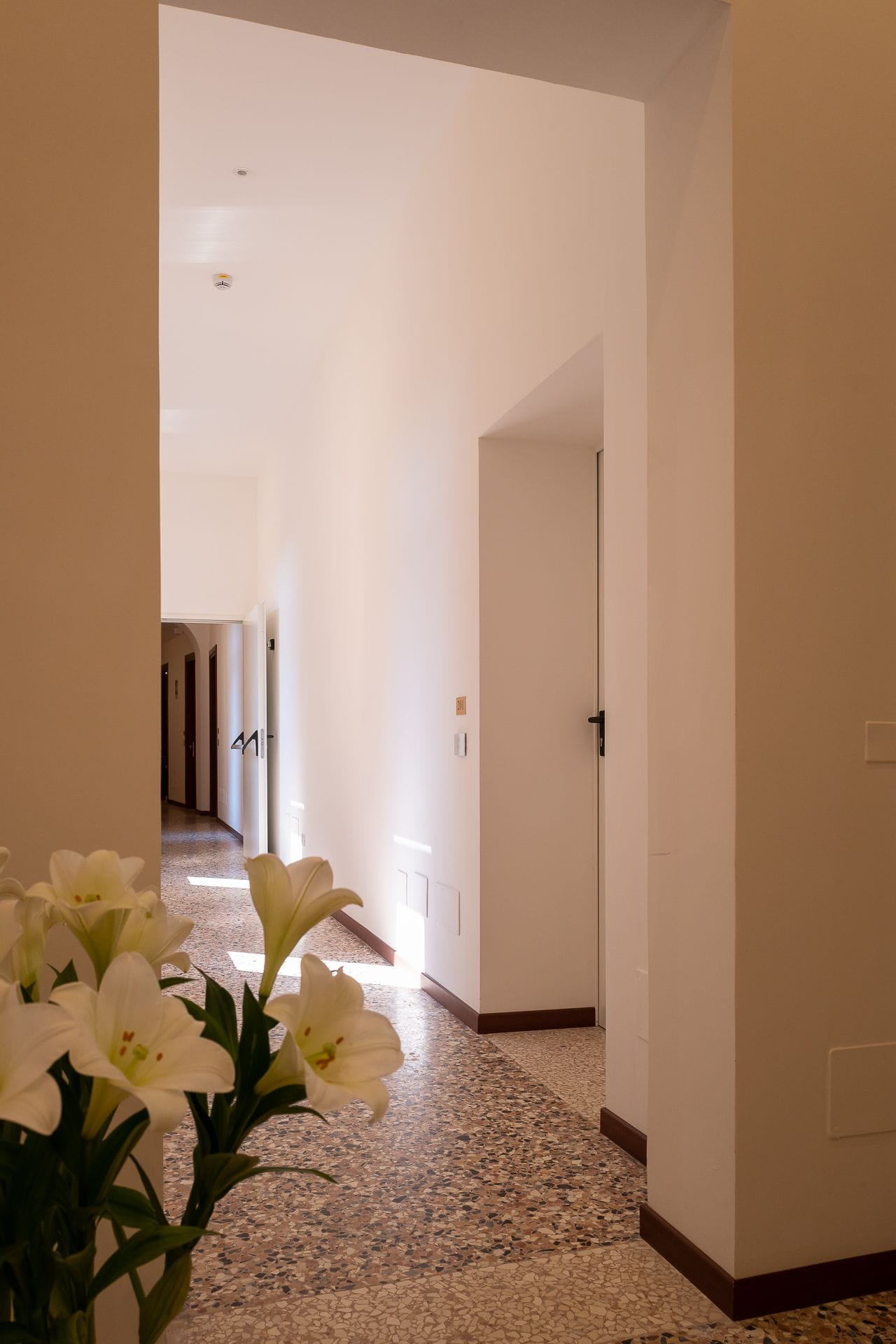 A hallway with white walls and a speckled floor, leading to a door marked with the number 41.