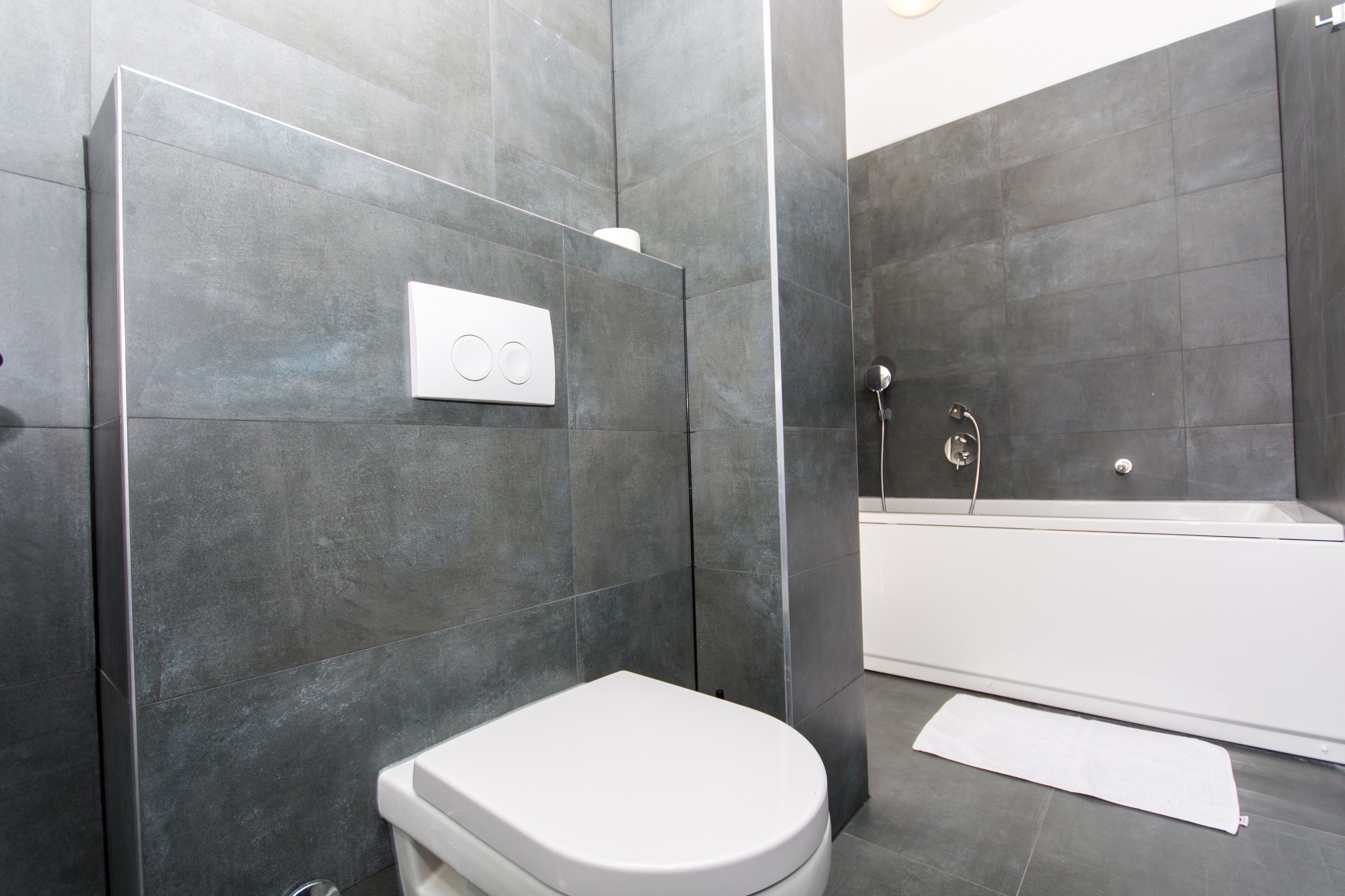 Een moderne badkamer met toilet, douche en bad.