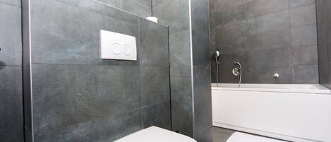 Een moderne badkamer met toilet, douche en bad.