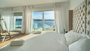 Una camera da letto con un letto grande, vista mare e un quadro sul pavimento.