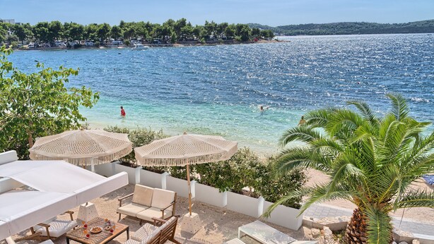 Un patio sul mare con posti a sedere all'aperto, ombrelloni e vista sul mare.