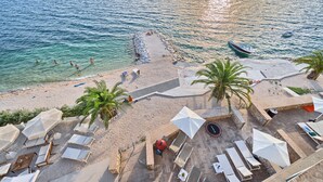Una spiaggia con acque cristalline, lettini, ombrelloni e una barca.