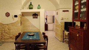 Un coin repas avec une table dressée pour quatre personnes, un mur en pierre et un buffet en bois doté de portes en verre.