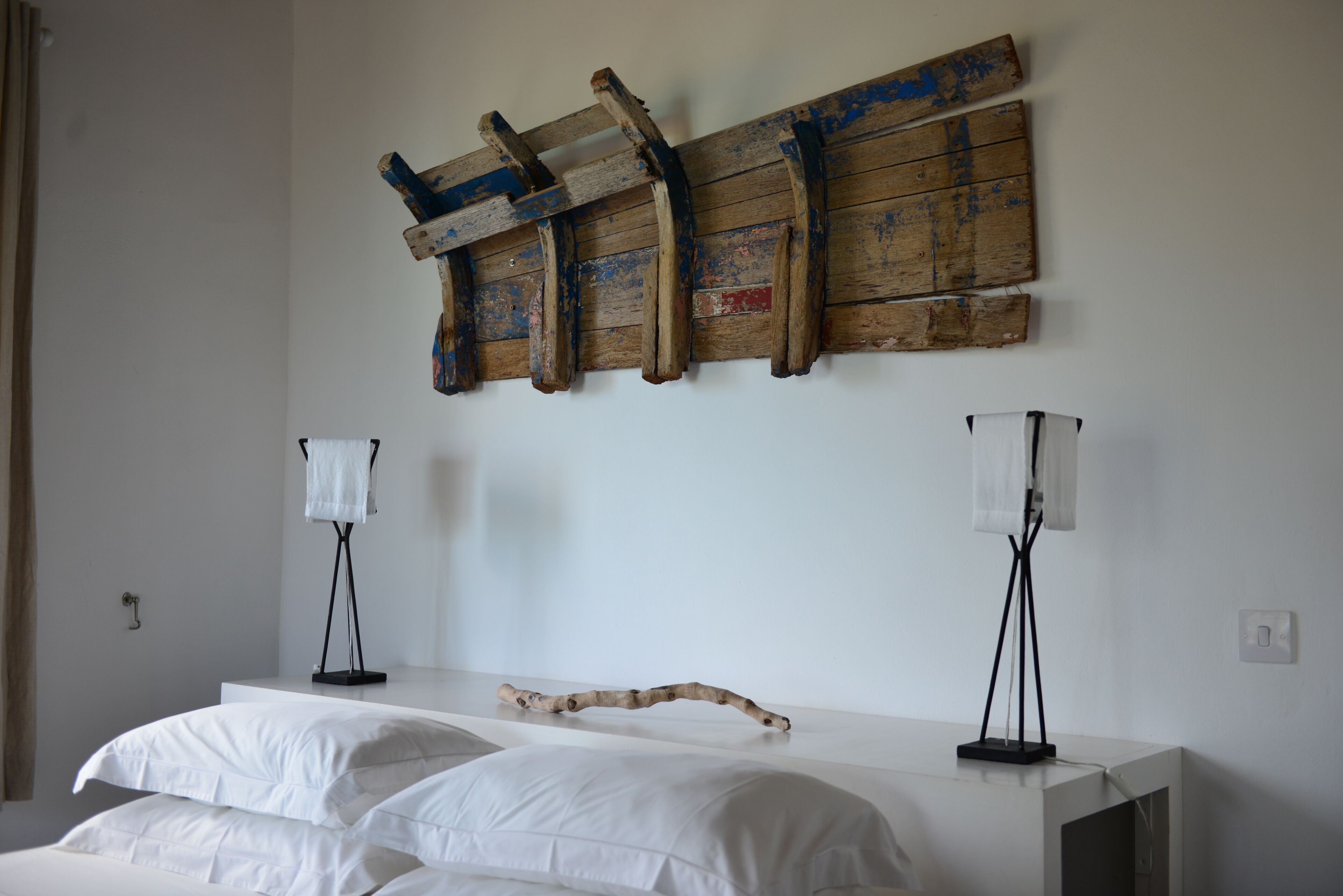 A bedroom with a bed, two bedside lamps, and a wooden wall art piece.