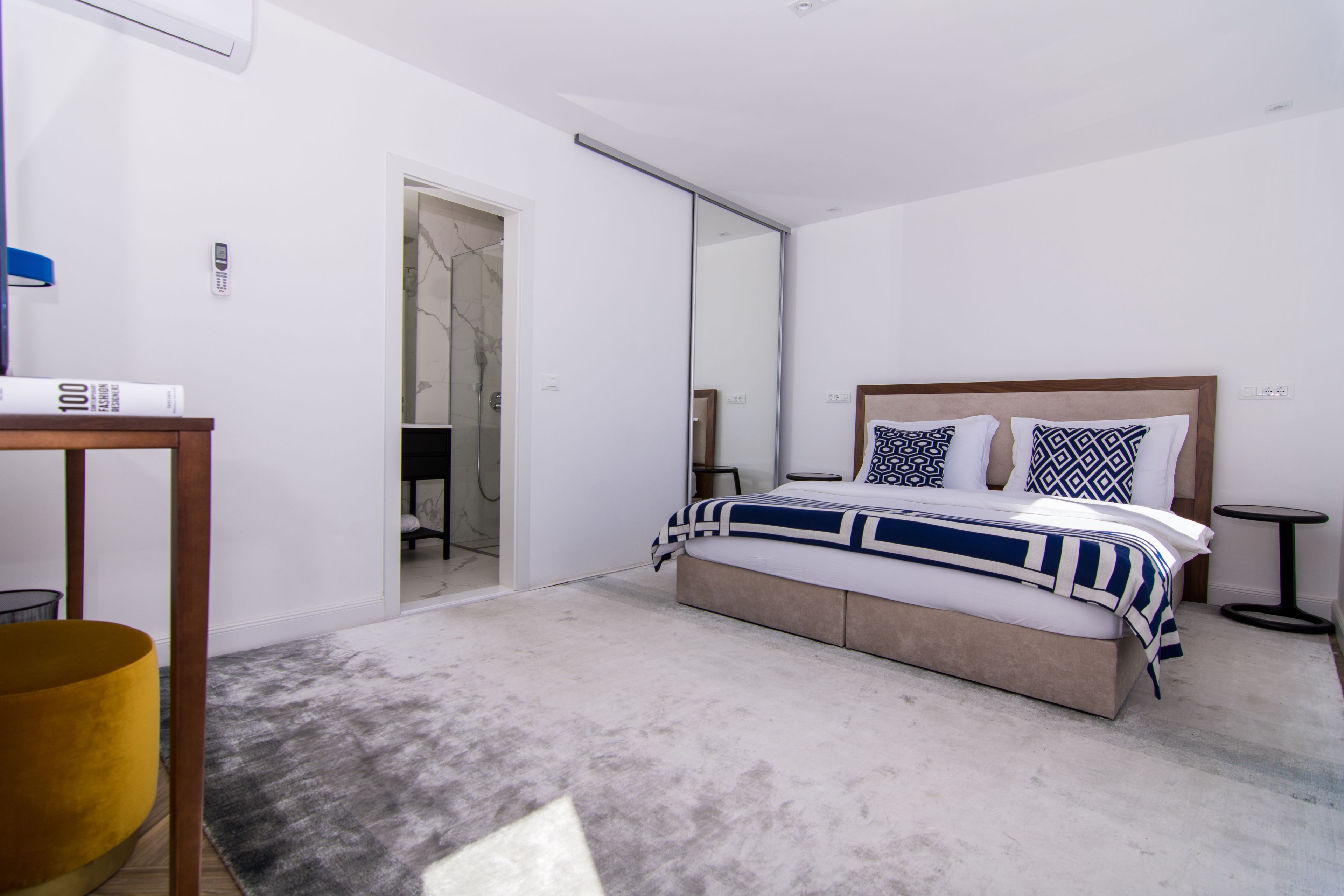 Un dormitorio moderno con una cama grande, una mesita de noche, un espejo y un armario.