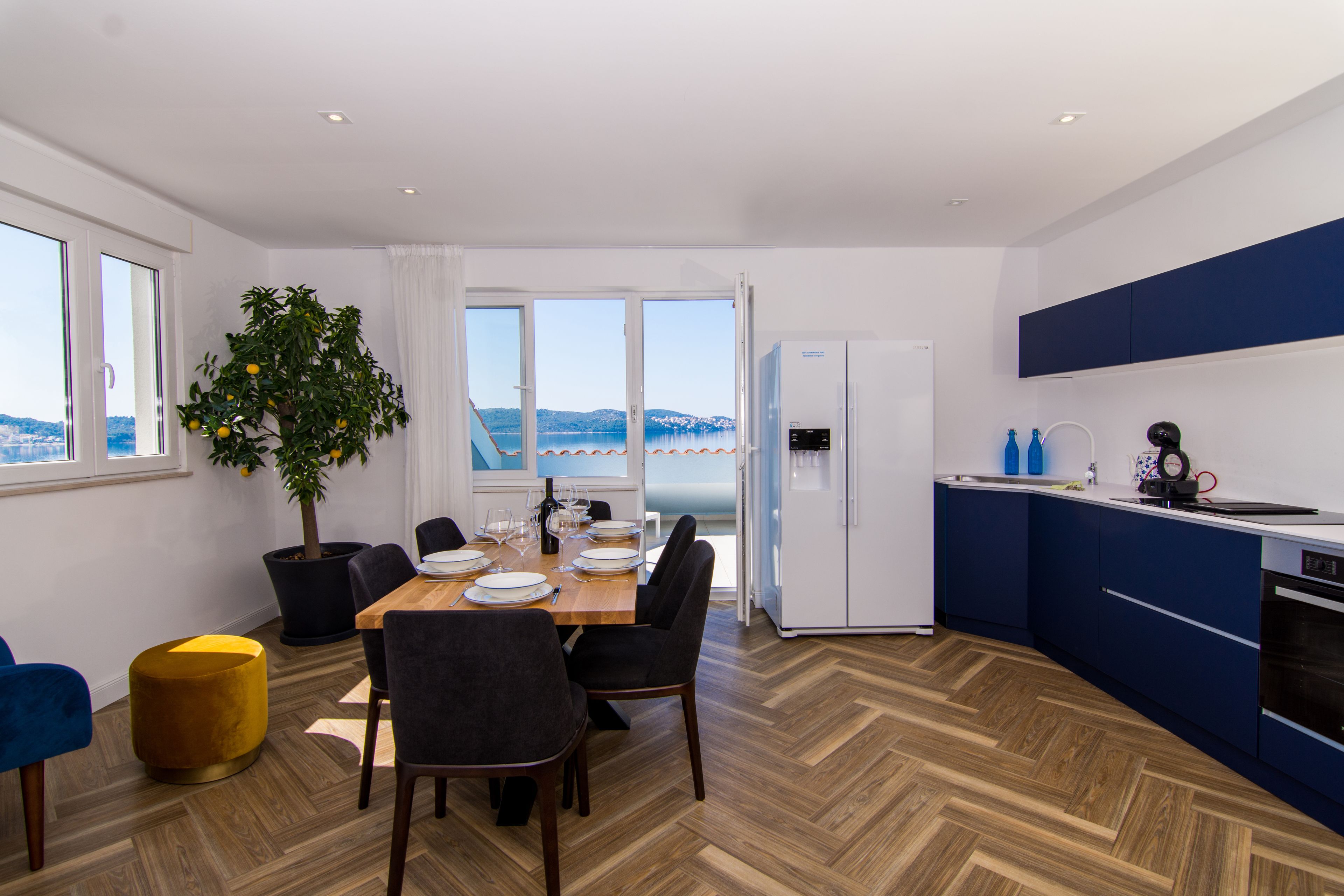 Eine moderne Küche mit Meerblick, ein Essbereich mit Tisch für vier Personen und ein Blumentopf.