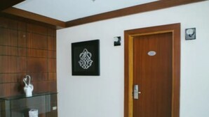 Una habitación con una puerta de madera, un aparador de vidrio y una obra enmarcada en la pared.