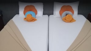 Una cama doble con ropa de cama blanca y dos almohadas, una con funda azul y otra con funda naranja.