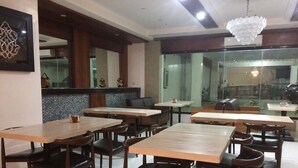 Un restaurante con varias mesas y sillas, un adorno en la pared y una lámpara colgante.