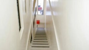 Un pasillo estrecho y bien iluminado con una escalera central.