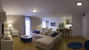 Una sala de estar moderna con un sofá, una mesa de centro redonda y un comedor con una cocina al fondo.