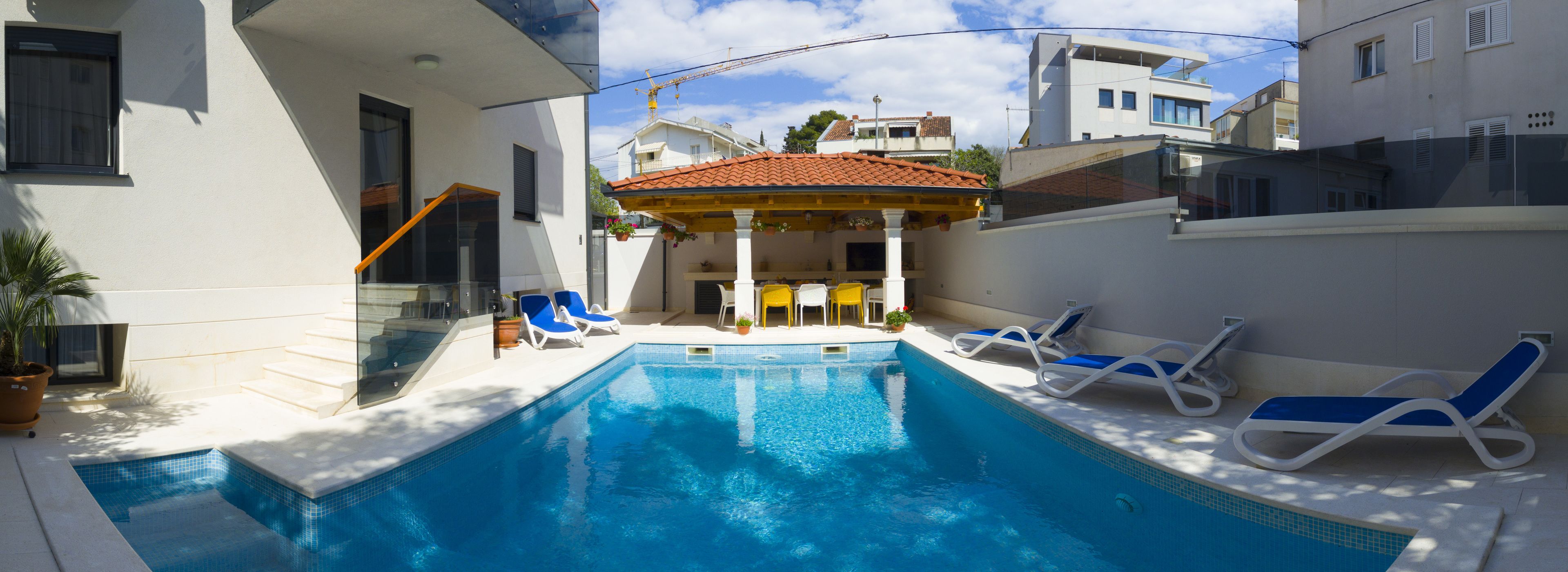 A swimming pool with lounge chairs and a covered seating area.
