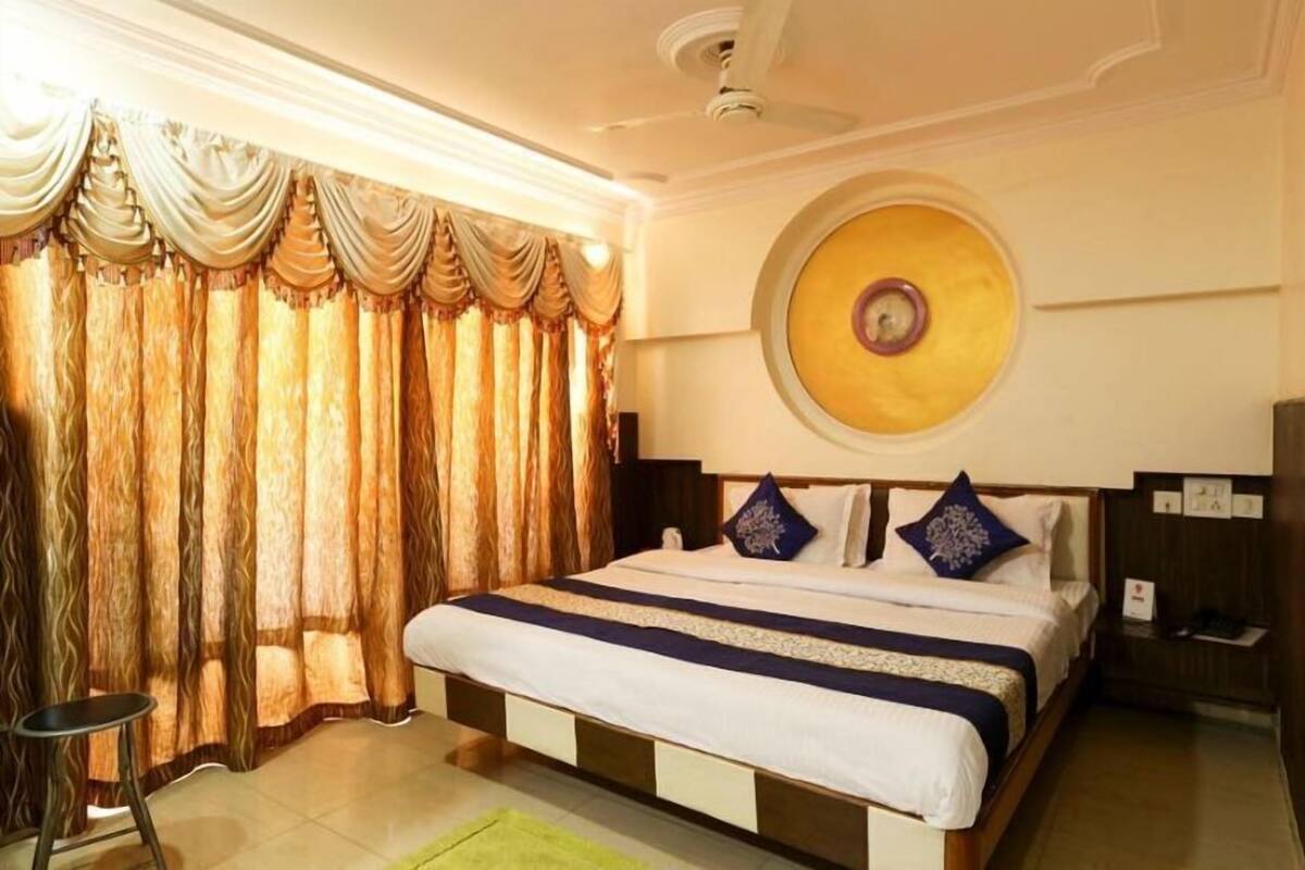 Une chambre d’hôtel avec un grand lit, un élément de décoration circulaire au mur et un ventilateur de plafond.