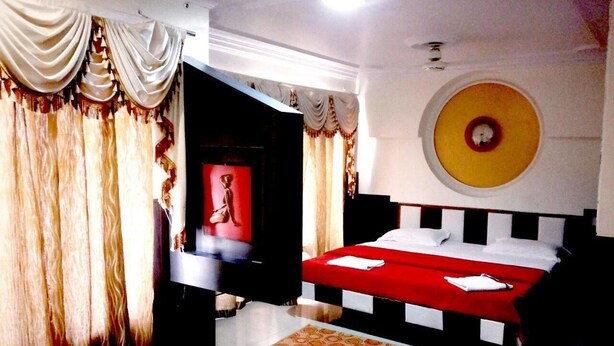 Une chambre d’hôtel avec un lit, un téléviseur et un élément de décoration rouge sur le mur.