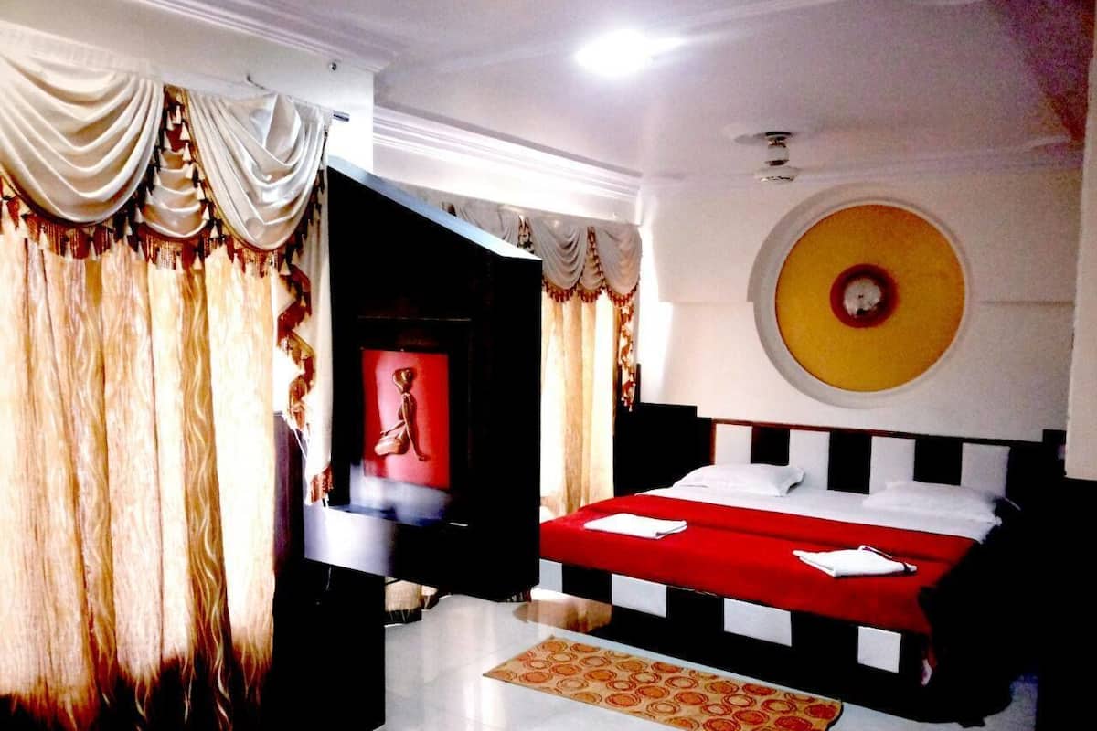 Une chambre d’hôtel avec un lit, un téléviseur et un élément de décoration rouge sur le mur.