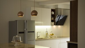A modern kitchen with a stainless steel refrigerator, a sink, and a bowl of fruit on the counter. - Presidential Suites Chica Cure (Split)