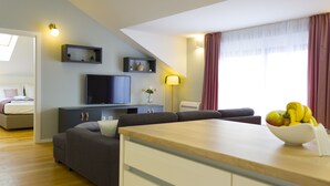 A modern living room with a flat-screen TV, a dining area with a fruit bowl, and a bedroom with a bed and a nightstand. - Presidential Suites Chica Cure (Split)