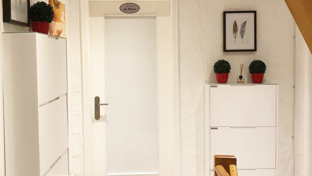 A hallway with a white door, a small potted plant, and a framed picture on the wall. - Apartment La Marie (Schwaebisch Gmuend)