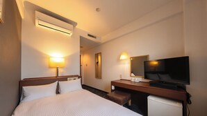 Ein Hotelzimmer mit Bett, Nachttischlampen, Fernseher, Schreibtisch und Minikühlschrank.