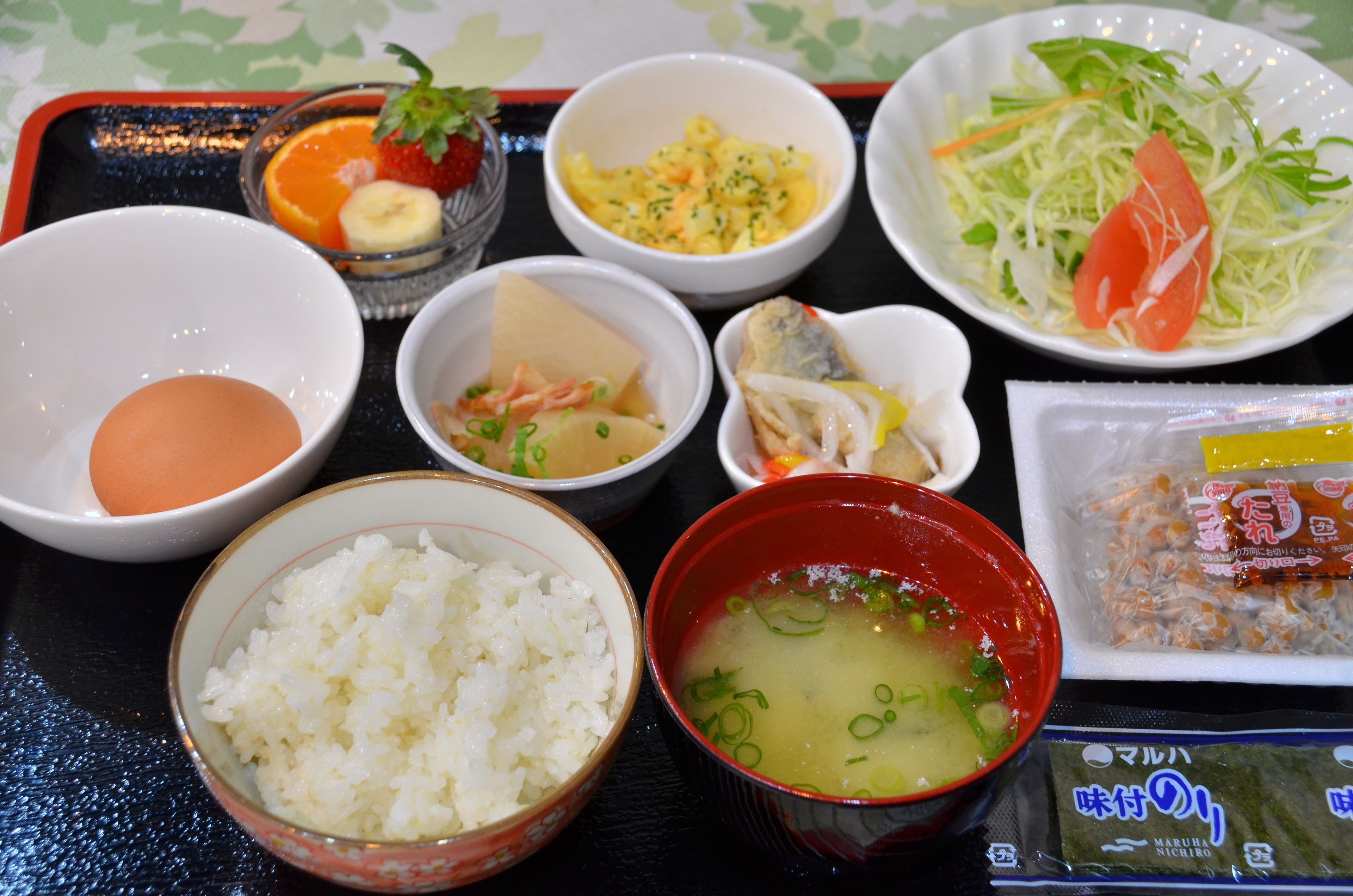 A tray with various Japanese dishes including rice, soup, and a salad.
