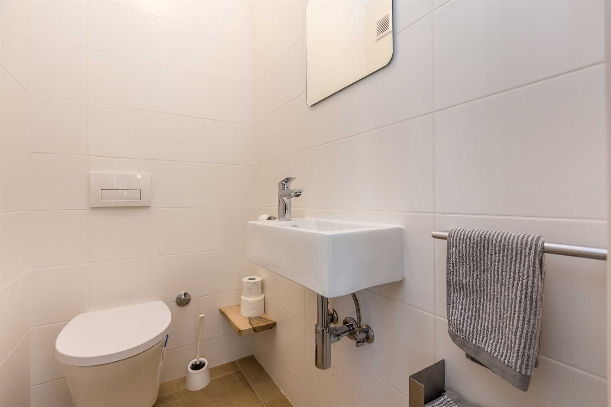 A small, modern bathroom with a toilet, sink, and towel rack.