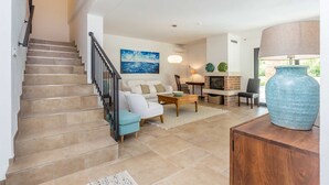A spacious living area with a staircase, a fireplace, and a large vase on a wooden table. - Holiday house RASOPASNO (Rasopasno)