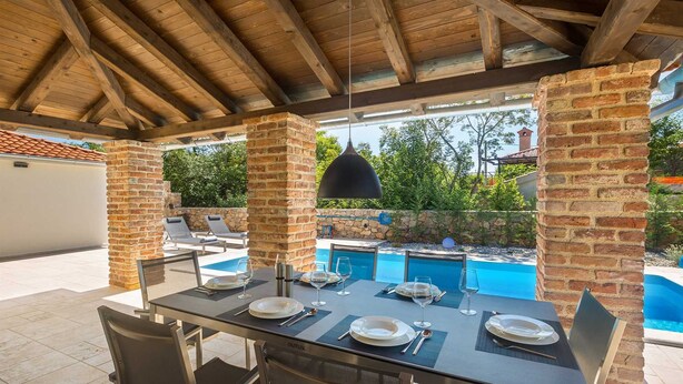 An outdoor dining area with a pool, brick pillars, and a covered ceiling. - Holiday house RASOPASNO (Rasopasno)