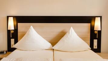 Una cama doble con cabecera de madera, dos lámparas de noche y una mesita de noche con un teléfono.