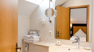 A modern bathroom with a skylight, a toilet, a sink with a mirror, and a towel rack.